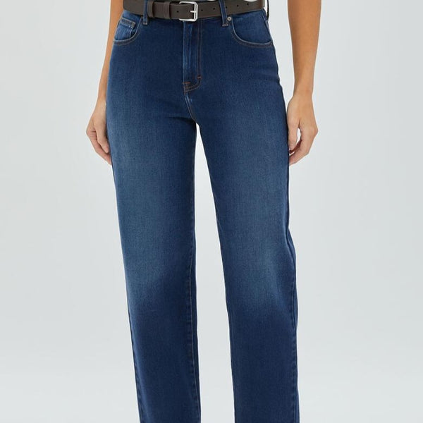 front view of the model wearing the tracey clean straight jeans in dark wash. shows the mid rise. also shows the front pockets, the zipper closure and the clean look of the jeans. 