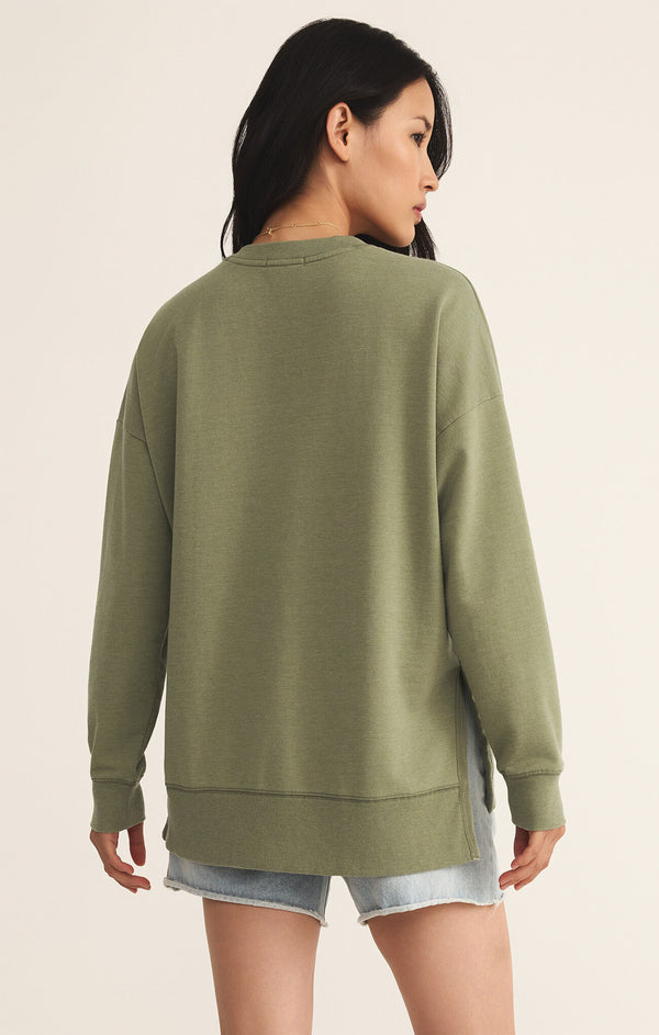 back view of the model wearing the modern v neck weekender. shows the side slits. also shows the ribbed hems, the green color and the oversized fit. 