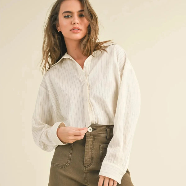 front view of the model wearing the olivia pin stripe button down shirt. shows the collared neckline. also shows the button down closure, the cropped length and the boyfriend fit. 