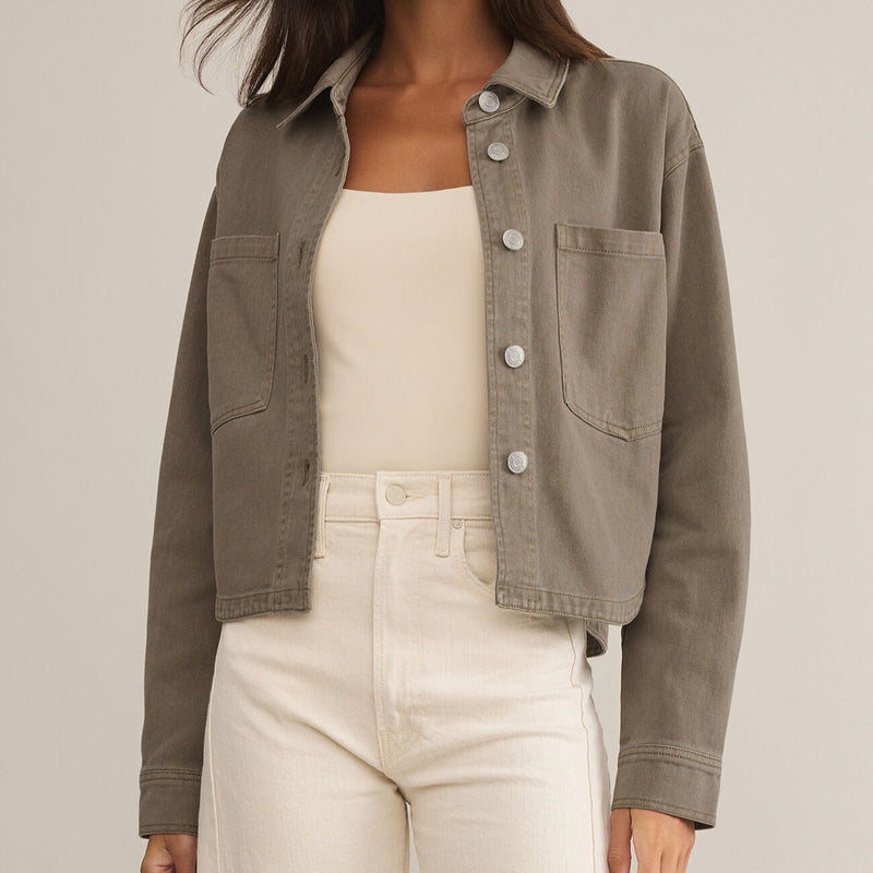 front view of the model wearing the all day cropped denim jacket. shows the cropped length. also shows the brownish color, the button down closure and the two front patch pockets.