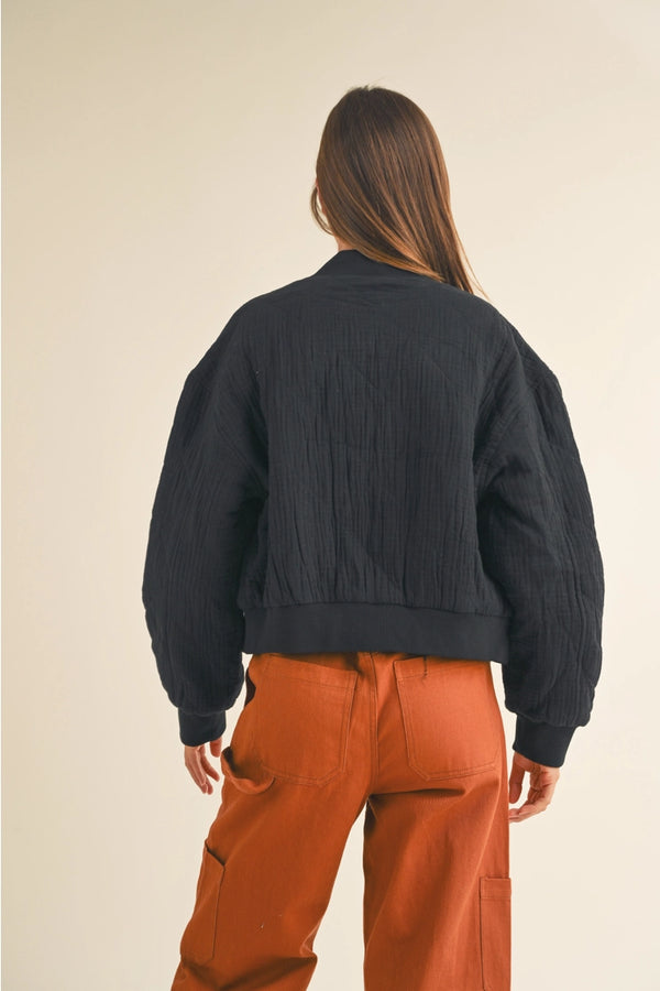 back view of the model wearing the norah quilted gauze bomber jacket. shows the relaxed fit. also shows the banded waist and cuffs and dropped shoulders. 