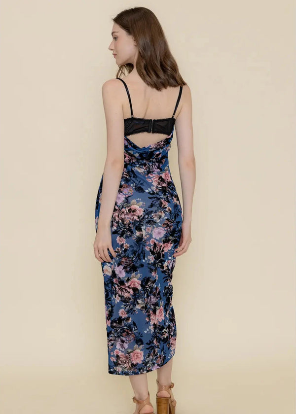 back view of the model wearing the vanessa velvet floral mesh midi dress. shows the midi length. also shows the back adjustable spaghetti straps, the back bra like closure and the all over floral print. 