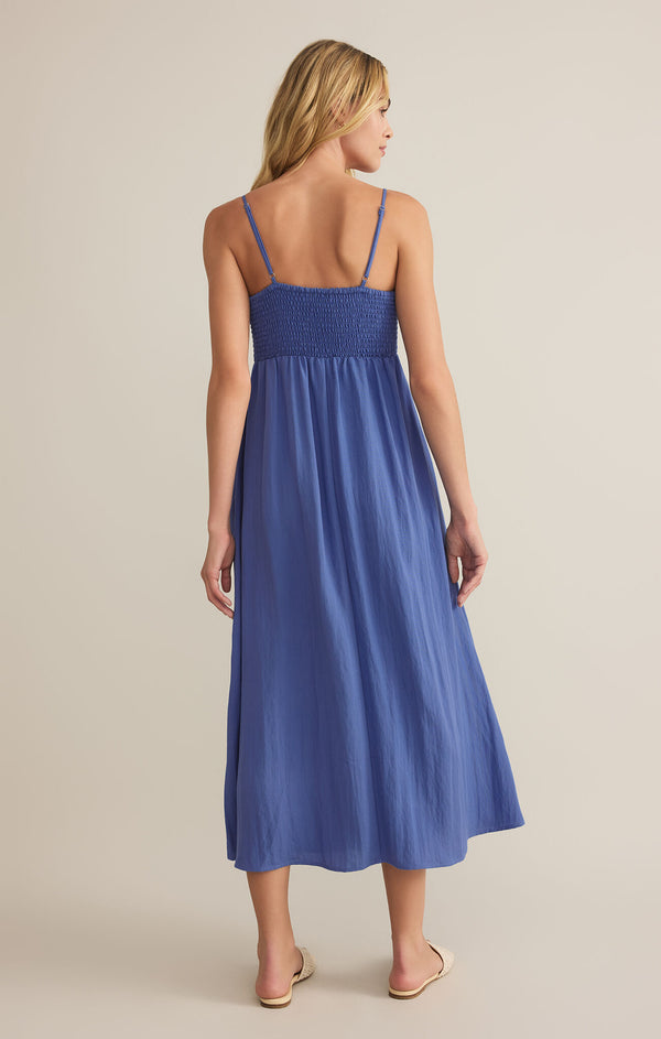 back view of the model wearing the beachside midi dress. shows the adjustable spaghetti straps. also shows the ruched top, the midi length and the blue color. 