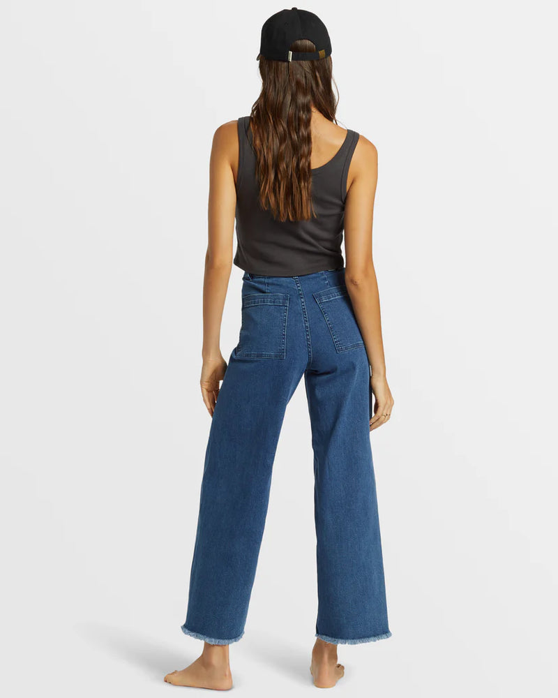 back view of the model wearing the free fall indigo wide leg jeans. shows the back square pockets. also shows the high rise waist, the bottom fray hem and the wide leg. 