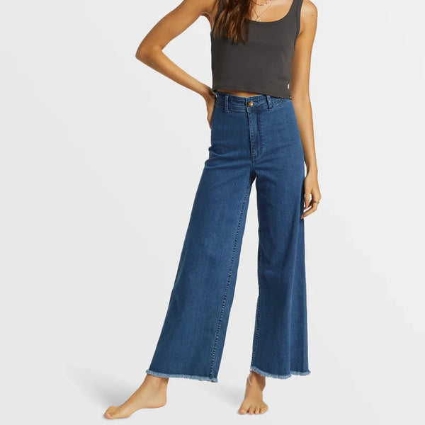 front view of the model wearing the free fall indigo wide leg jeans. shows the button closure. also shows the bottom raw hem, the high rise and the wide leg. 