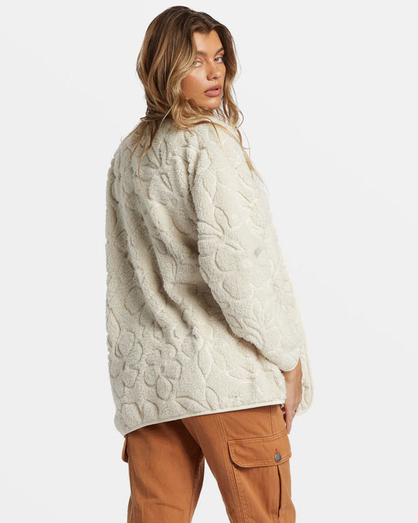 back view of the model wearing the fireside cozy buttoned fleece jacket. shows the embossed flowers throughout. also shows the oversized fit and the cream color. 