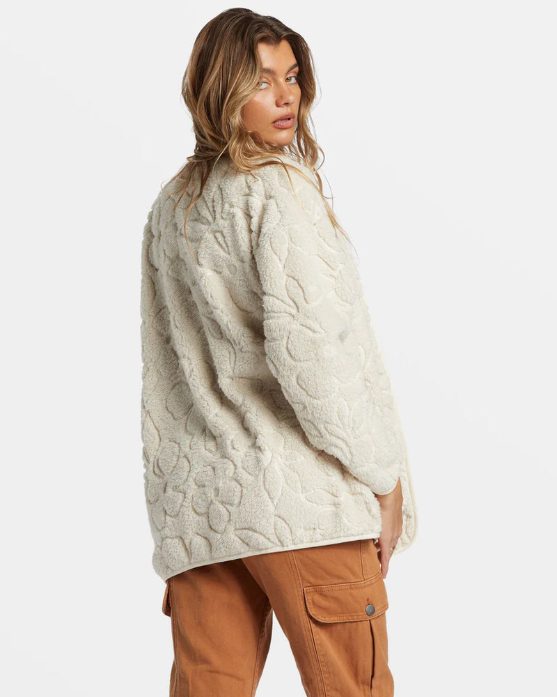 back view of the model wearing the fireside cozy buttoned fleece jacket. shows the embossed flowers throughout. also shows the oversized fit and the cream color. 