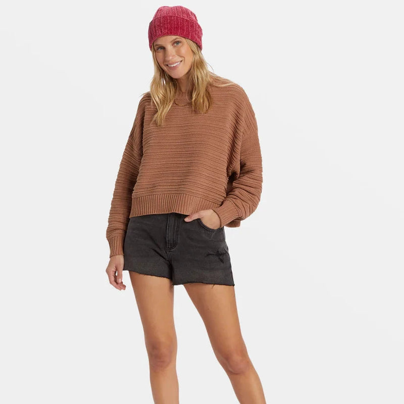 front view of the model wearing the evie sweater. shows the scoop neckline. also shows the brown color, the dropped shoulders, the relaxed fit and rib stitch design. 