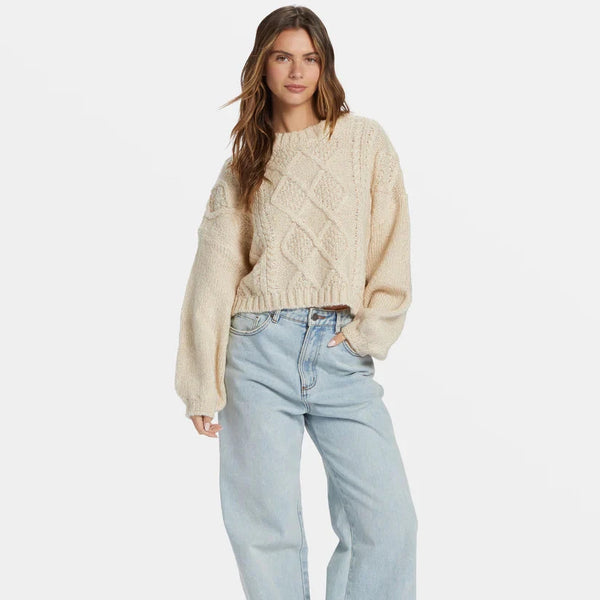 front view of the model wearing the modern love pullover sweater. shows the cable knit detail. also shows the scoop neckline, the dropped shoulders and the slight cropped length.