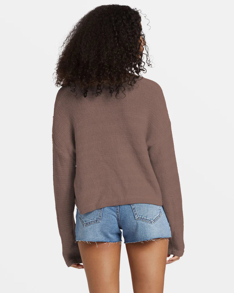 back view of the model wearing the shallow waters henley sweater. shows the dropped shoulders. also shows the long sleeves and that the back is little longer then the front. 