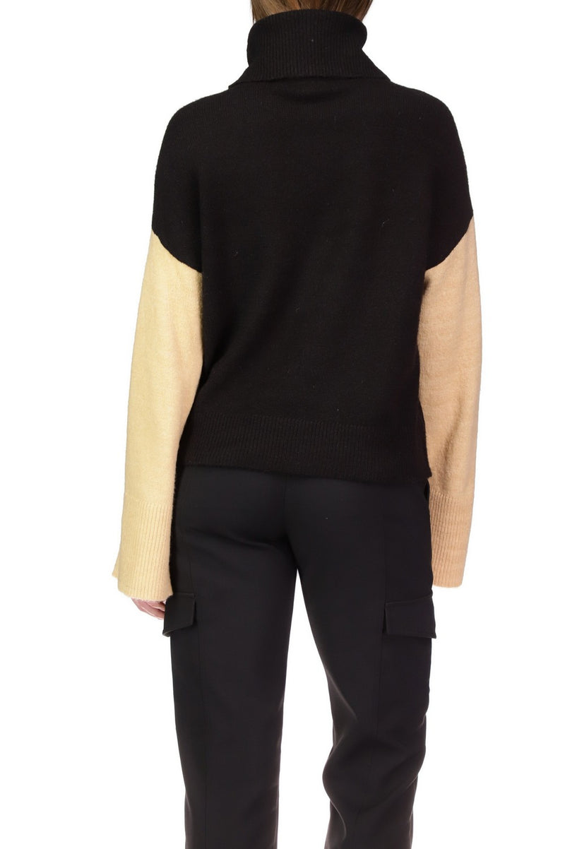 Back view of model wearing sweater. Shpws ribbed band bottom. Also shows turtleneck and colorblocking. 