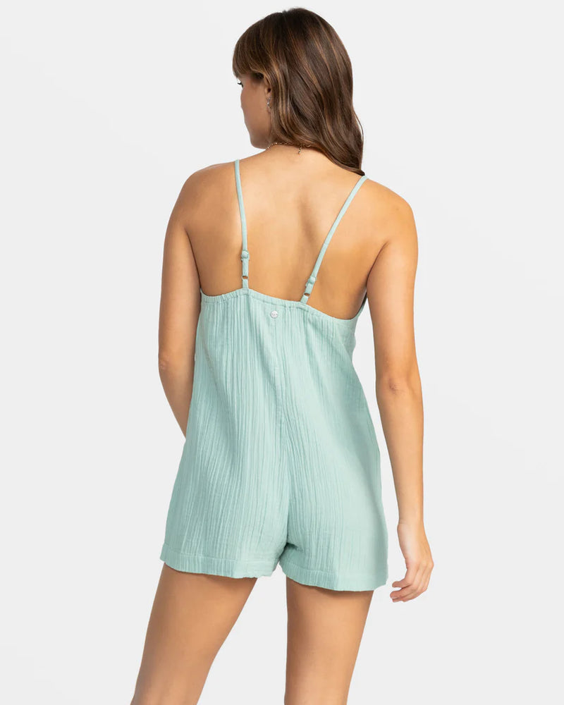 back view of the model wearing the sunshine haze v neck romper. shows the adjustable straps. also shows the one piece with shorts, and the cotton fabric. 