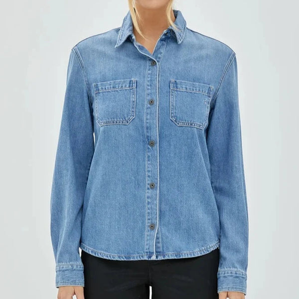 front view of the model wearing the abbey denim shirt. shows the collared neckline. also shows the front button closure, the round bottom hem, and the two front patch pockets. 