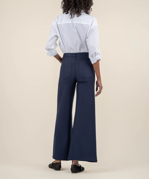 back view of the model wearing the meg high rise wide leg trousers in navy. shows the back patch pockets. also shows the navy color, the wide leg and the high rise waist. 