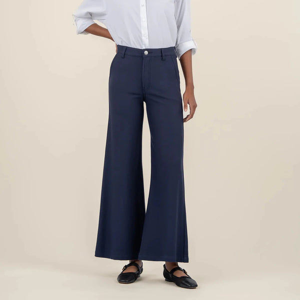 front view of the model wearing the meg high rise wide leg trousers in navy. shows the button closure. also shows the wide leg, the high rise waist and the belt loops. 