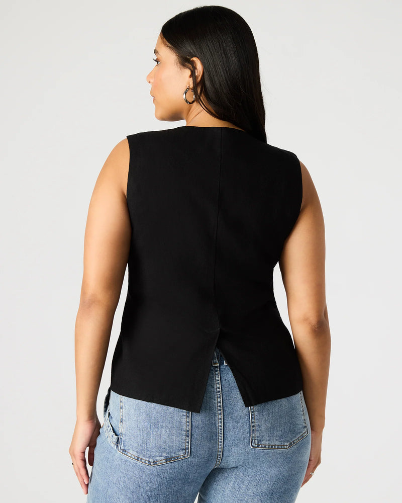 back view of the model wearing the wesley vest top. shows the bottom slit. also shows the top is sleeveless and the the black color.