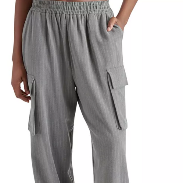 model wears a loose fitting grey pant with elastic waist and hand in pocket at waist