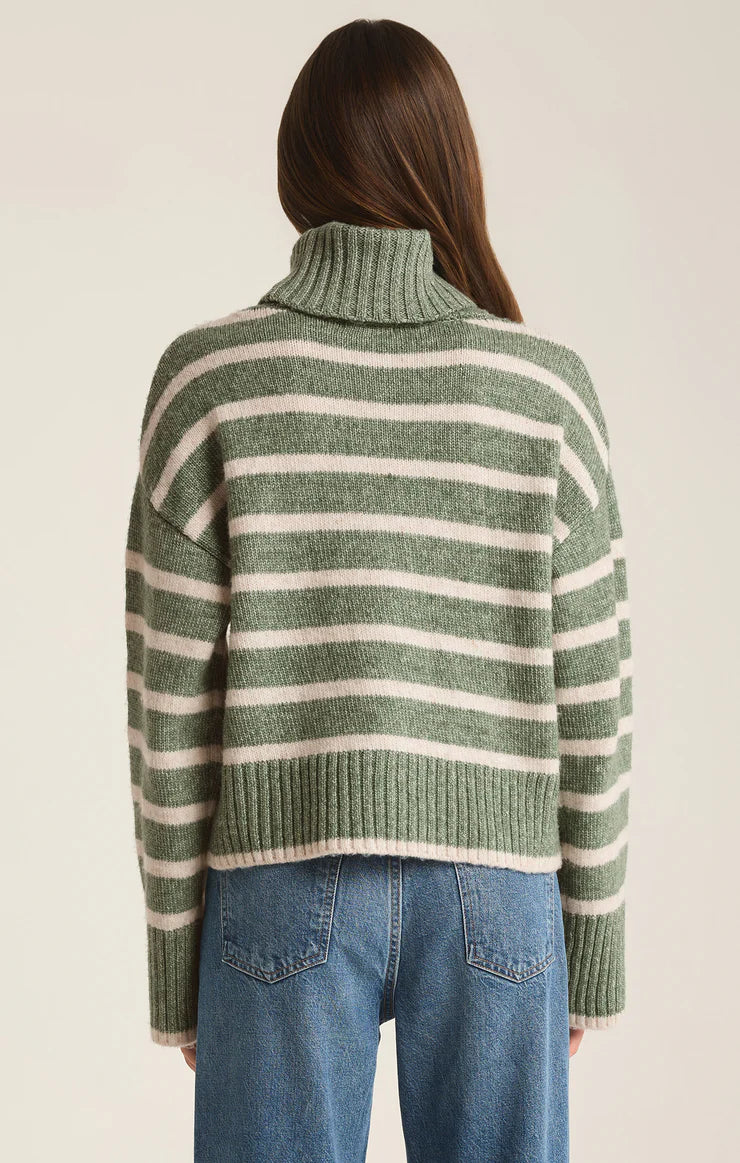 back view of the model wearing the josephine stripe sweater. shows the bigger turtleneck. also shows the white a green striped design, the wider sleeve and the ribbed detailing. 