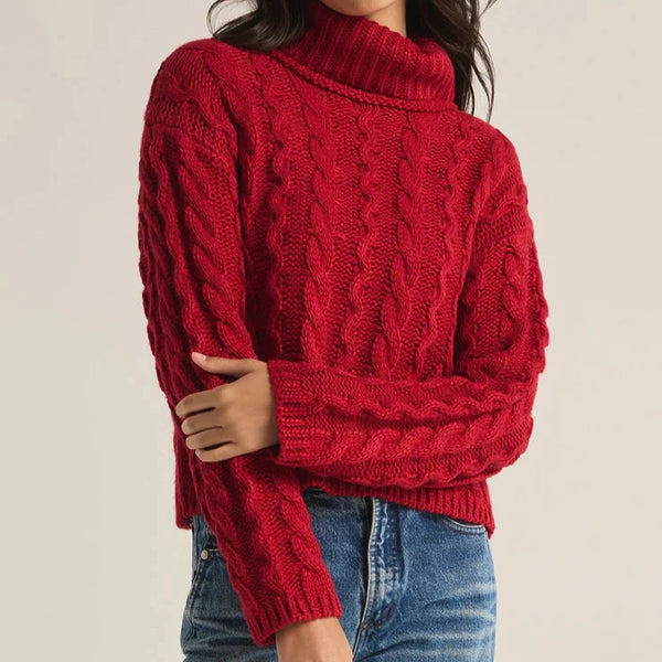 front view of the model wearing the tied to you sweater. shows the cable knit design. also shows the turtleneck, the waist length and the ribbed detailing. 