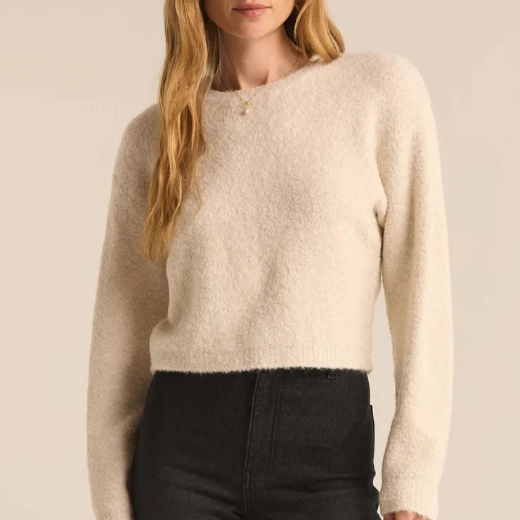 front view of the model wearing the destiny sweater in this winter white. shows the crew neckline. also shows the dropped shoulders, the waist length and the ribbed detailing. 