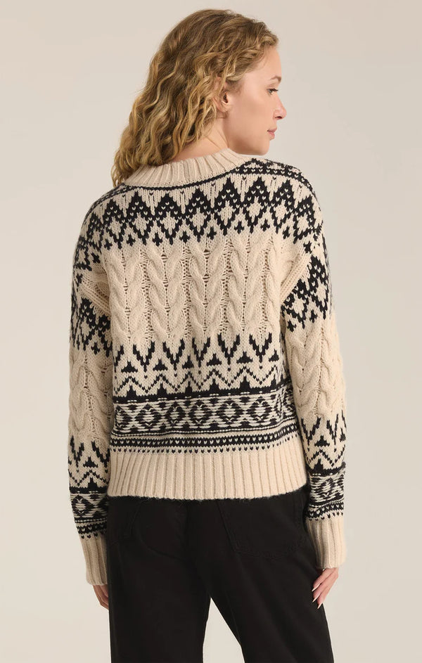 back view of the model wearing the garland fairisle sweater. shows the cable knit detailing. also shows the fun pattern and crew neckline. 