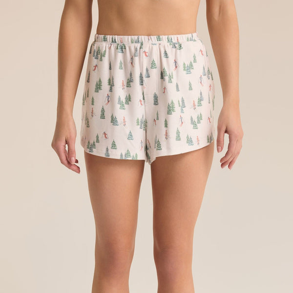 front view of the model wearing the preston alpine shorts. shows the little trees and skiers on the shorts. also shows the high rise, the elastic waistband, and the relaxed fit. 