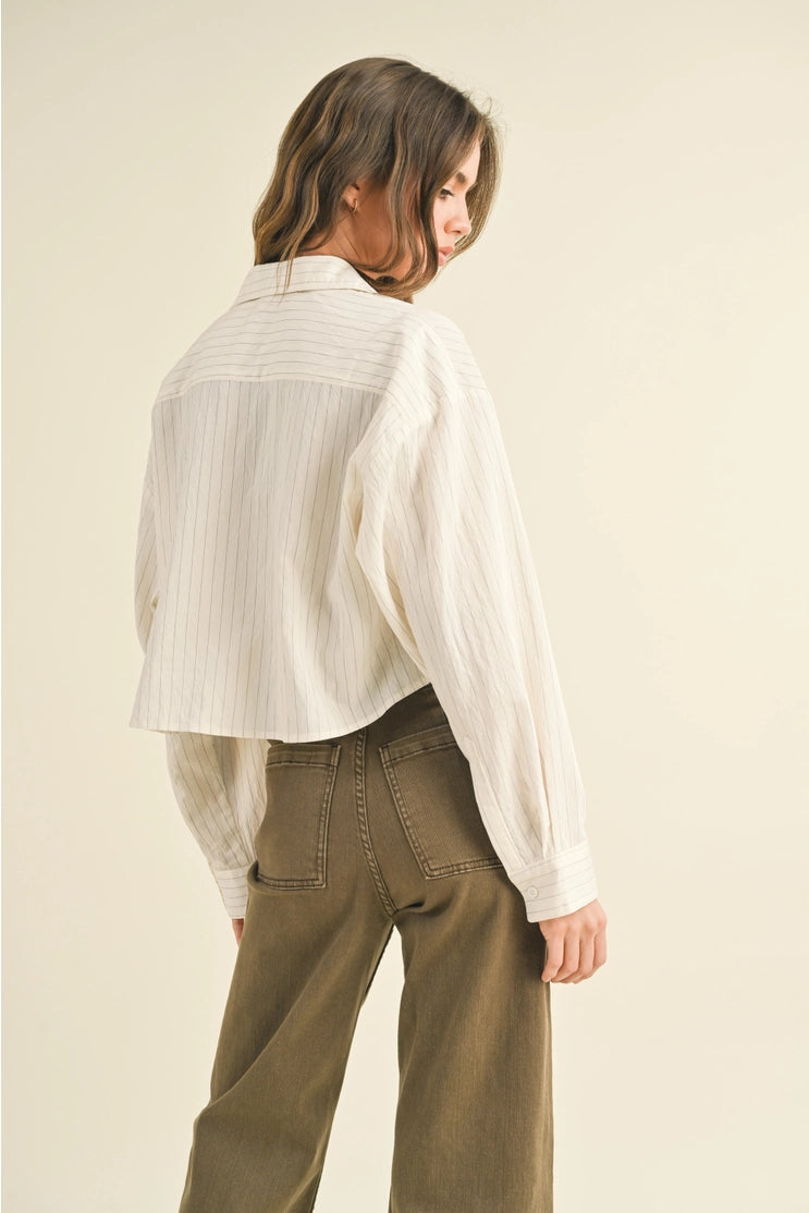 back view of the model wearing the olivia pin stripe button down shirt. shows the collared neckline. also shows the rounded back hem, the cropped length and pin stripe design throughout. 