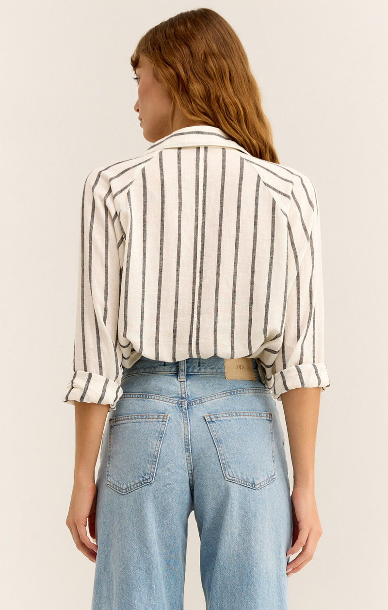 back view of the model wearing the perfect line top. shows the pin stripe design. also shows the model has the sleeves cuffed, also has the shirt tucked in. 