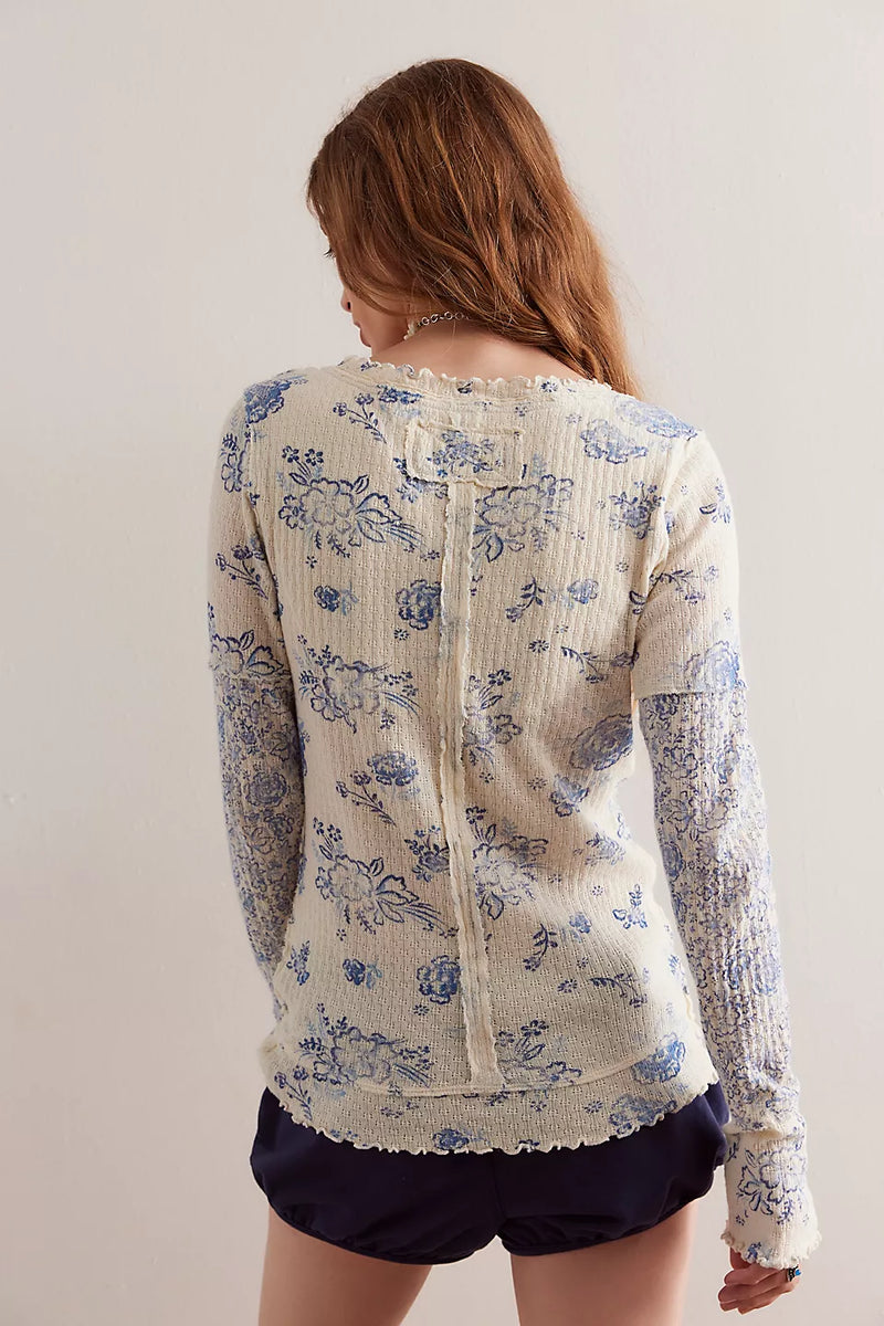 back view of the model wearing the clover printed thermal. shows the exposed seaming. also shows the layered hem, the lettuce trim and the all over print. 