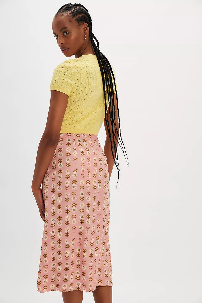 back view of the model wearing the analise printed midi skirt. shows the mid length. also shows the all over flower print, the mid-rise and A silhouette. 