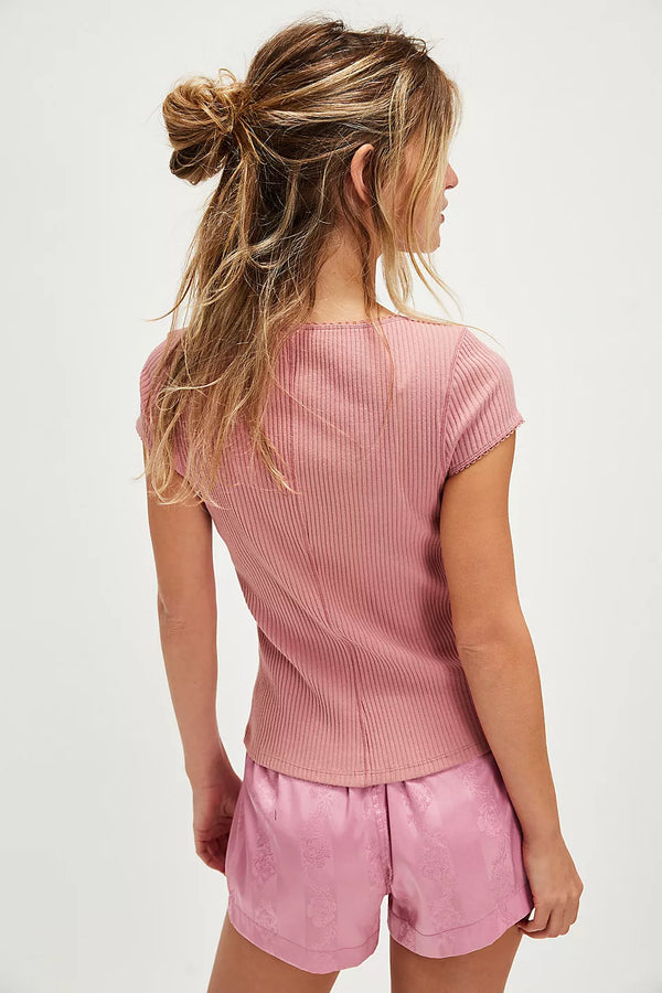 back view of the model wearing the most wanted cardi. shows the seam down the middle. also shows the pink color, the ribbed detailing and capped sleeves. 