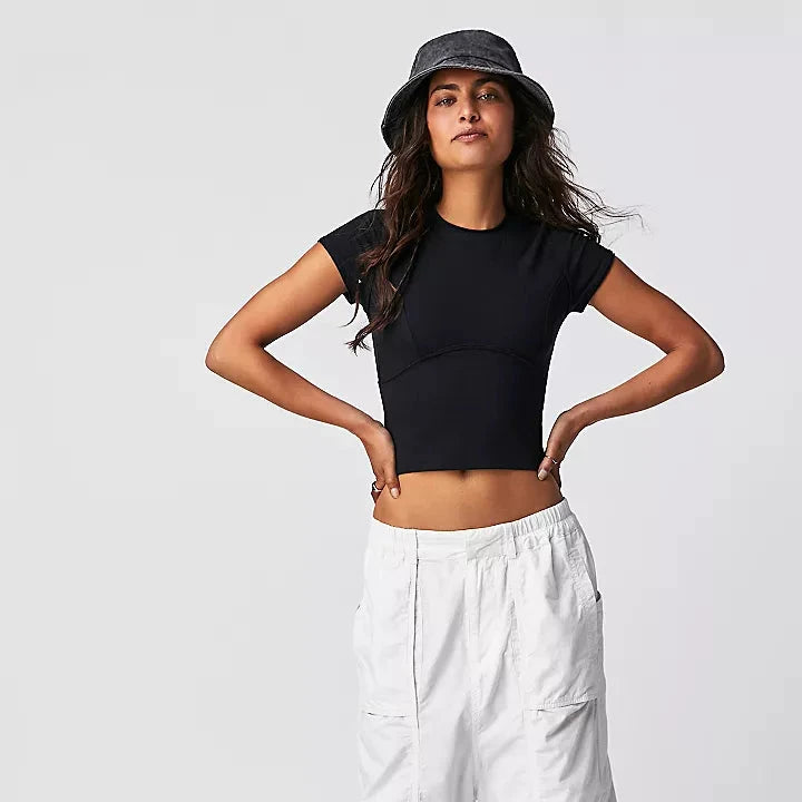 front view of the model wearing the protagonist tee in black. shows the the scoop neckline. also shows the slight cap sleeves, the exposed seams, & the cropped silhouette. 