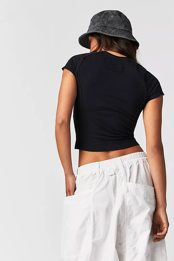 back view of the model wearing the protagonist tee in black. shows the cropped silhouette. also shows the exposed seams & the slight cap sleeves. 