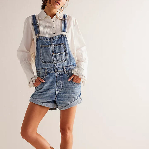 front view of the model wearing the ziggy shortalls. shows the bib silhouette. also shows the rolled bottom hem, the bottom side pockets, and the front patch pocket. 