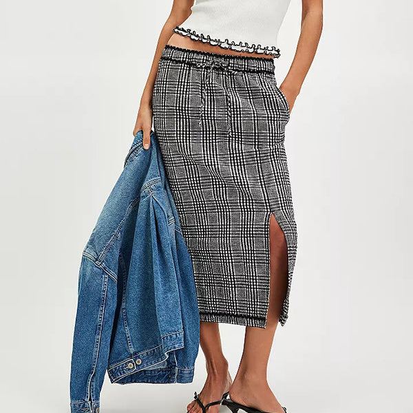 front view of the model wearing the penelope gingham midi skirt. shows the vented slit. also shows the midi length, the pull on style, the tie drawstring and the black and white checkered print. 