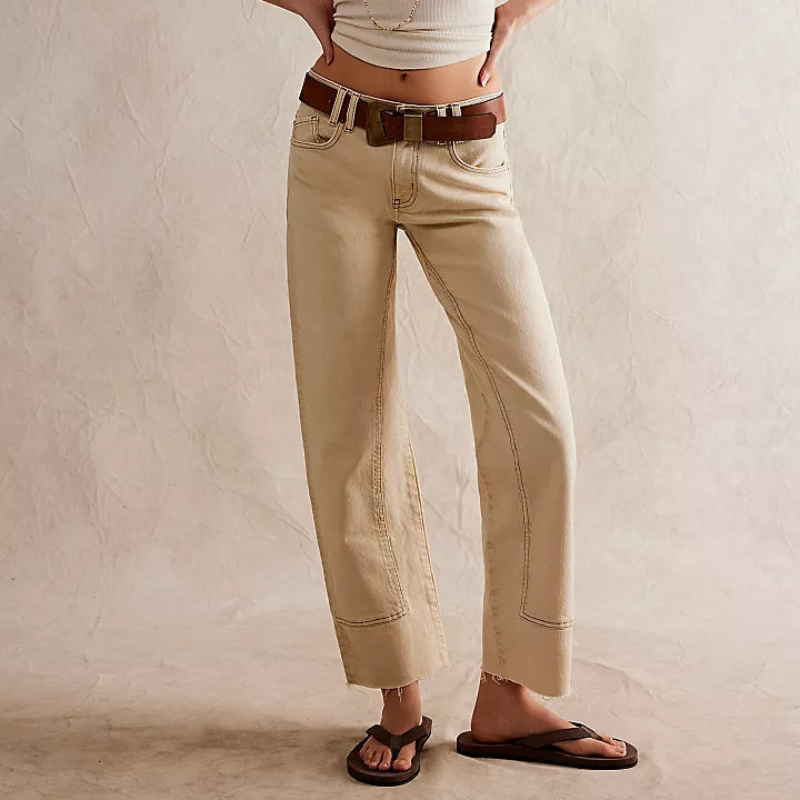 front view of the model wearing the risk taker mid rise jeans. shows the tan/beige color. also shows the straight leg, the mid rise, and the utility seaming throughout. 