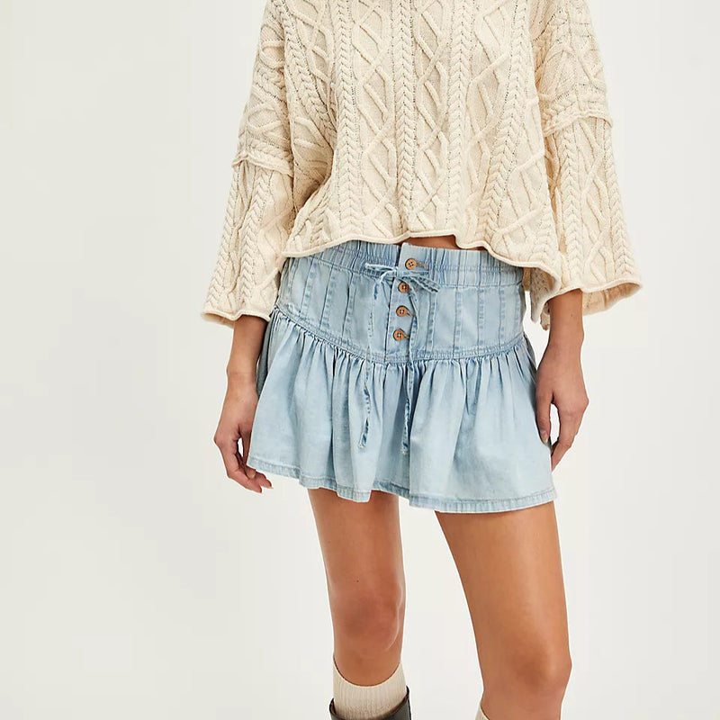 front view of the mode; wearing the roselle denim mini skirt. shows the front button fly. also shows the drawstring, the aline silhouette and the dropped waist. 