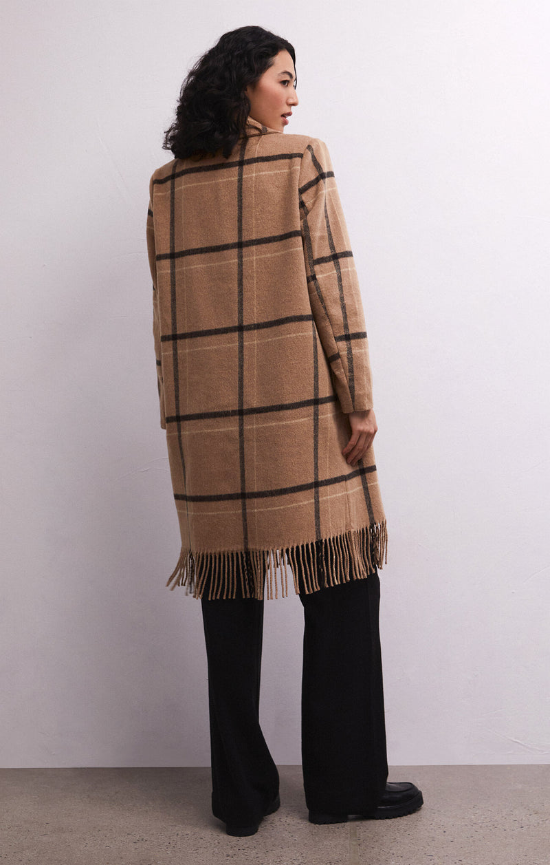 Back view of model wearing coat. Shows the fringe detail at the bottom. Also the mid length and the brown, black & white plaid. 