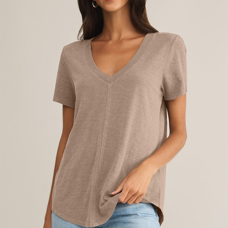 front view of the model wearing the asher v neck tee. shows the exposed seams. also shows the v neckline, the bottom curved hem and the short sleeves. 