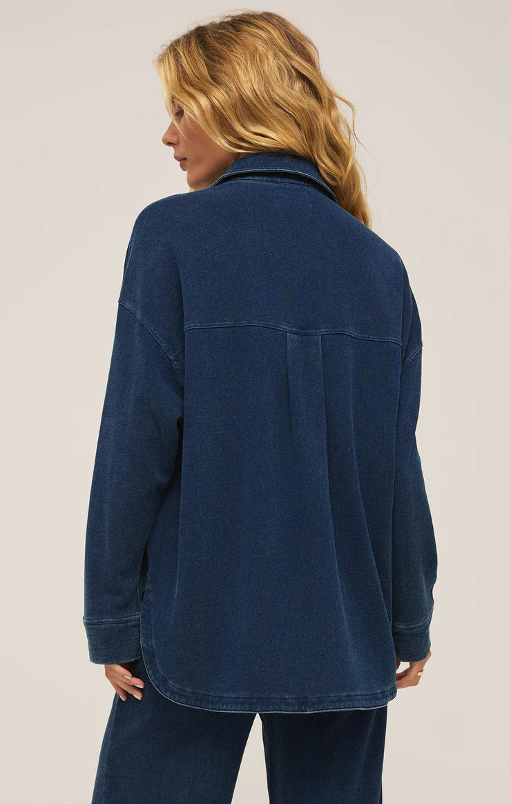 back view of the model wearing the all day knit denim jacket. shows the curved hem. also shows the collar, the dropped shoulders and the oversized fit.