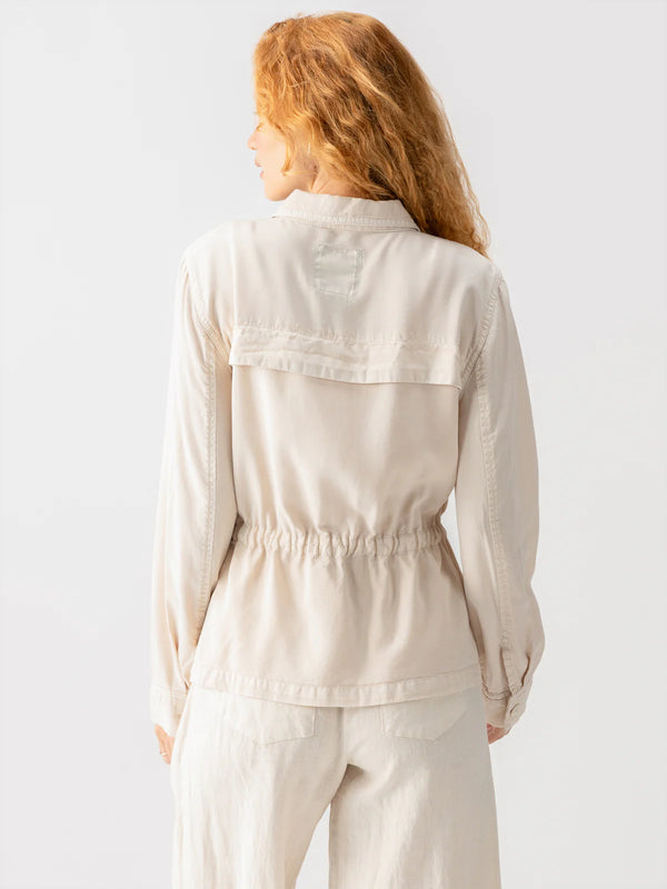 back view of the model wearing the lora surplus jacket. shows the little flap detail. also shows the the synched waist, the button closure on the cuffs, and the traditional collar. 