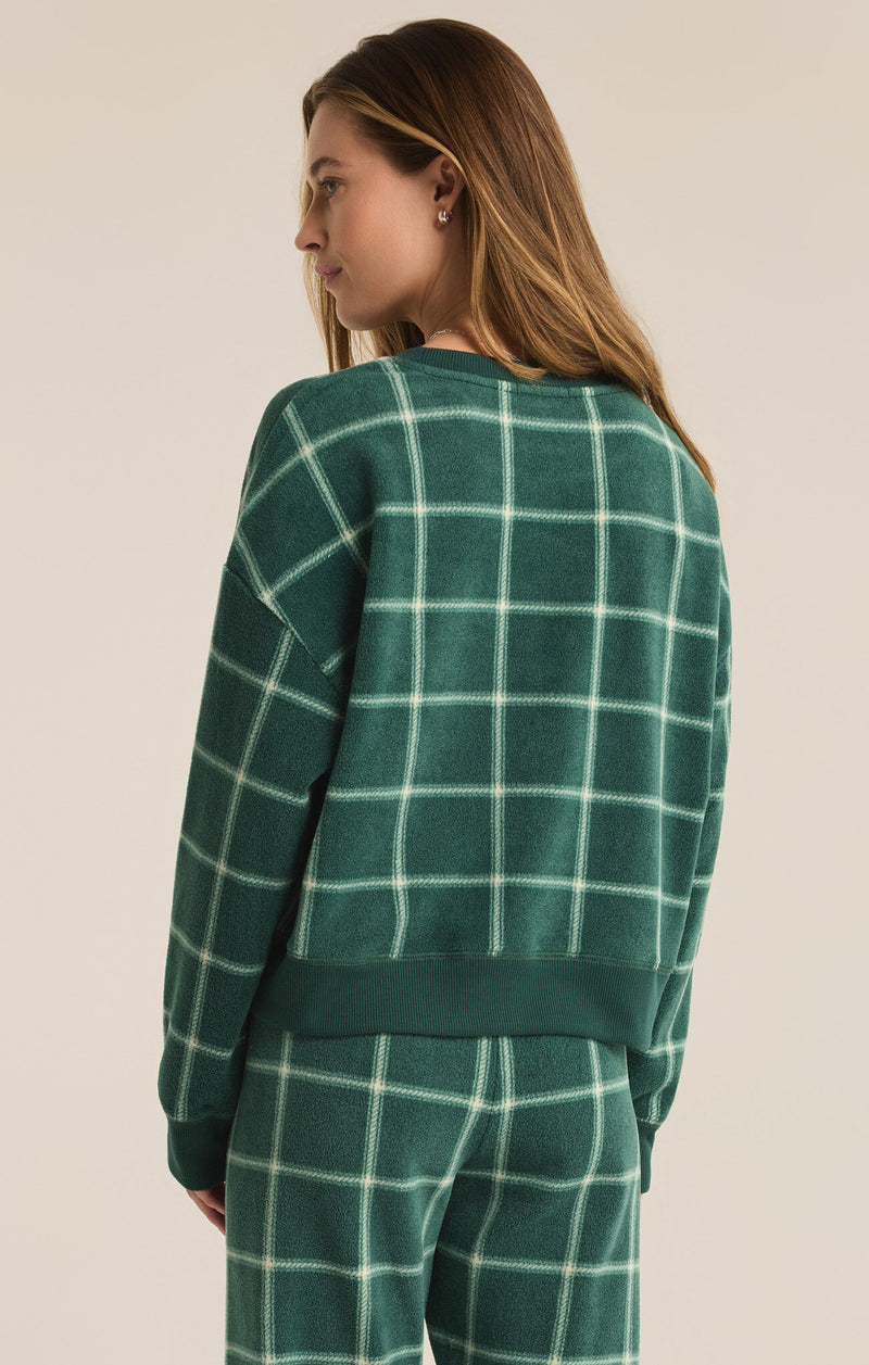 back view of the model wearing the plaid long sleeve top. shows the dropped shoulders. also shows the relaxed fit, the crew neckline and the ribbed detailing on the bottom hem. 