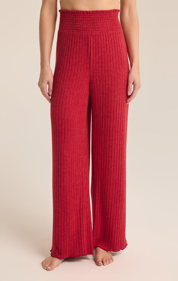 front view of the model wearing the dawn smocked rib pant. shows this beautiful red color. also shows the high waist, the smocked waist, the lettuce trim and the ribbed detailing. 