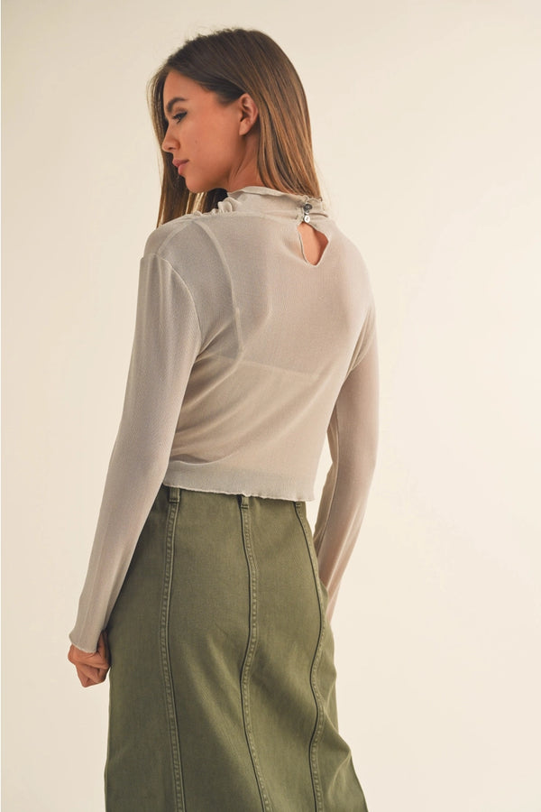 back of the lisa mesh sparkle long sleeve. shows the keyhole by the neckline. also shows the button closure on the neck, the semi ruffle on hem and cuffs and the cropped length. 