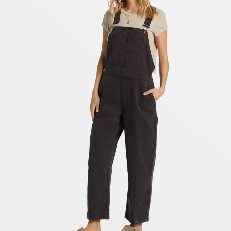 front view of the sand canyon overalls. shows the adjustable straps. also shows the multiple pockets, the relaxed fit and the black color. 