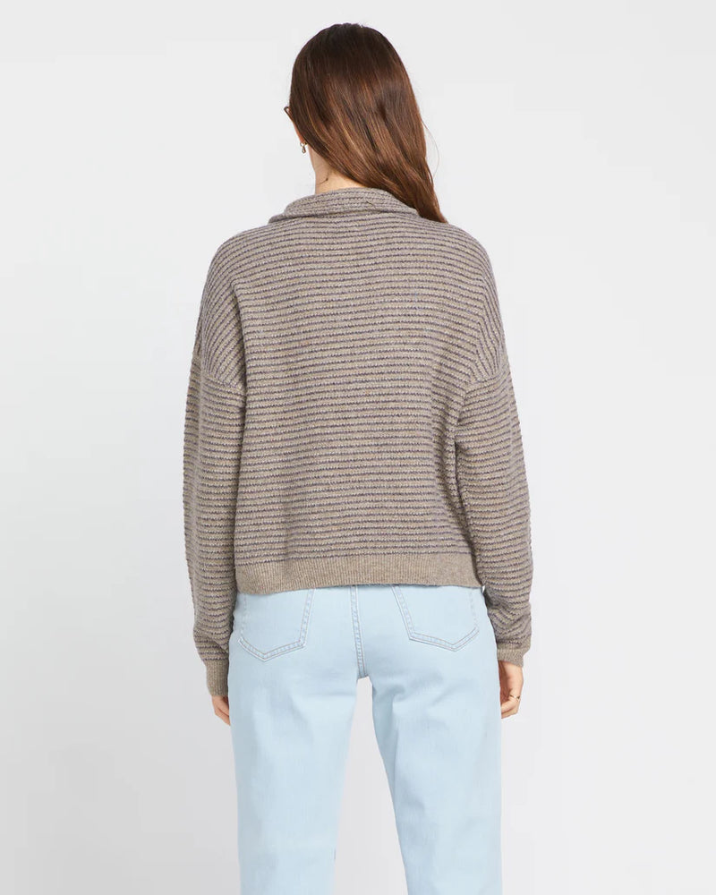 back view of the model wearing the sun of sand sweater. shows the dropped shoulders. also shows the boxy fit nd the collar. 