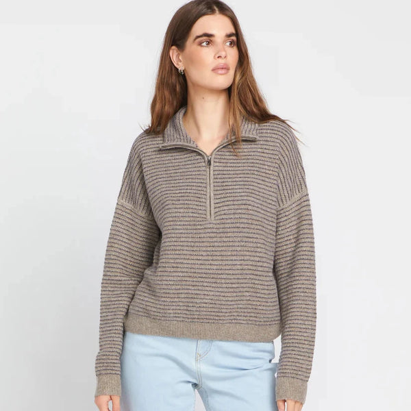 front view of the model wearing the sun of sand sweater. shows the mock neck collar. also shows the partial zipper, the dropped shoulders, and the boxy fit. 