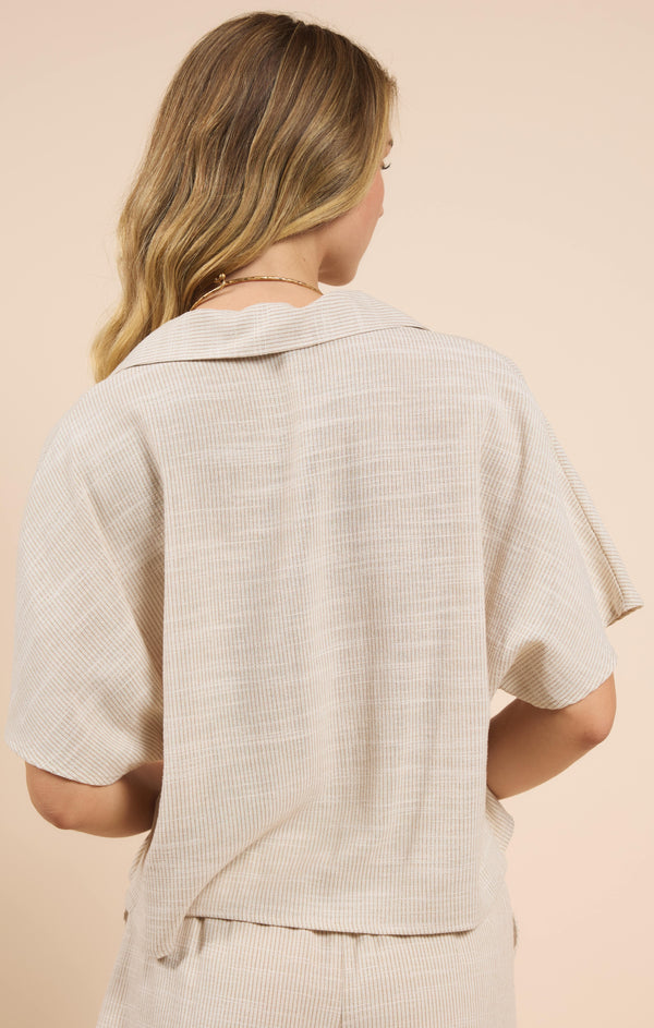 back view of the model wearing the mojave placket top. shows the collar. also shows the oversized fit, that t is longer in the back and ribbed detailing. 