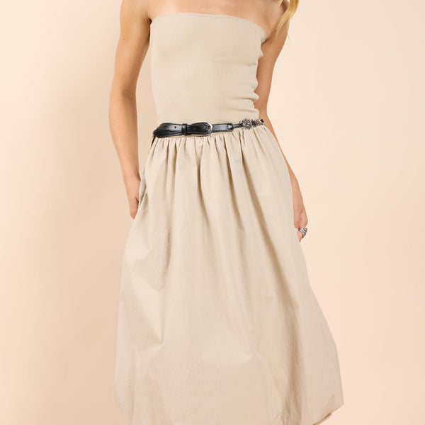 front view of the model wearing the happier now strapless bubble dress. shows the dress is strapless. also shows the ribbed detailing on the top, the bubble skirt and the beige color. 