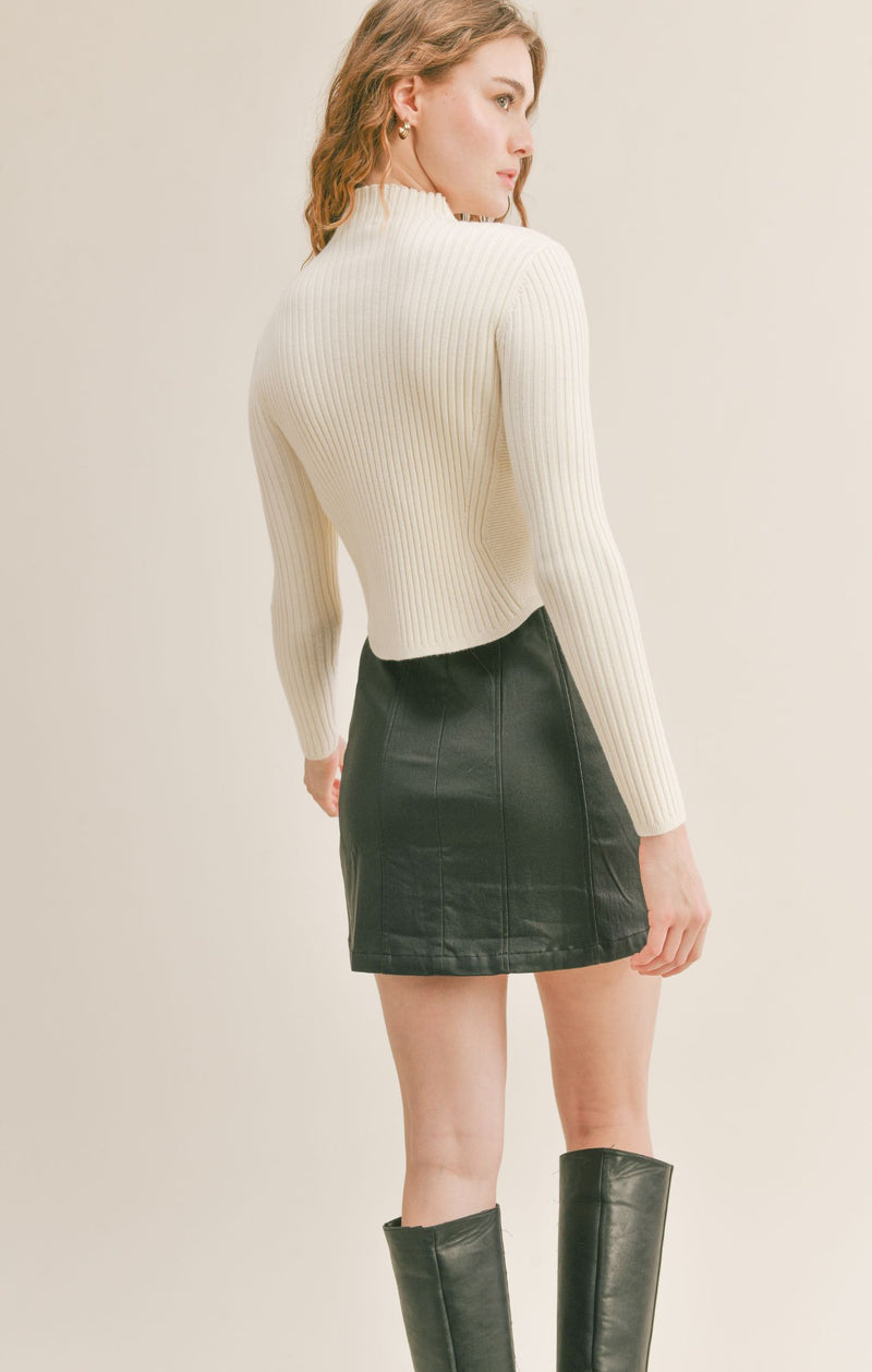 Back view of model wearing sweater. Shows that the back hem is longer. Also shows the ribbed knit detail. 